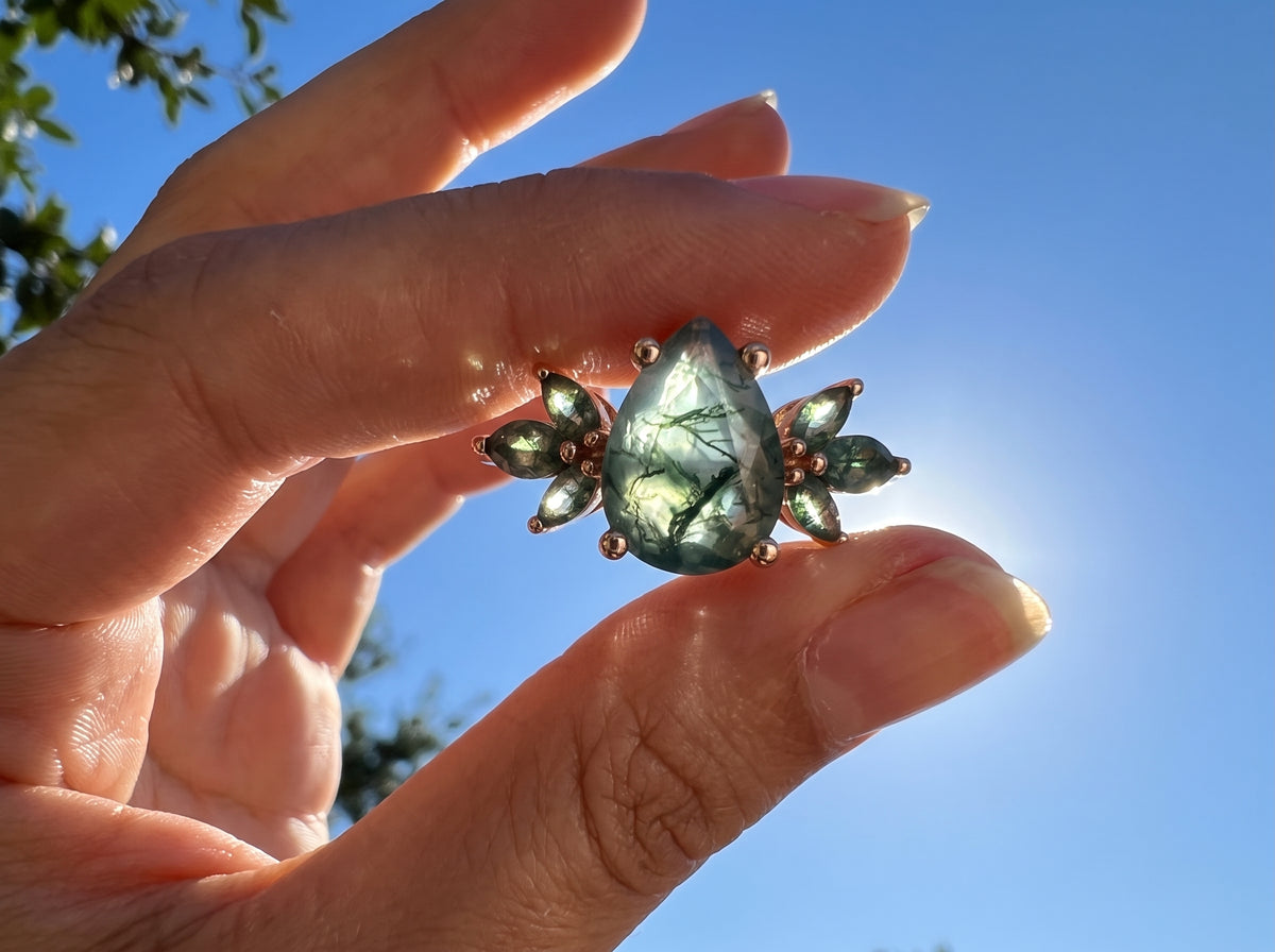 Green moss agate ring held against a blue sky
